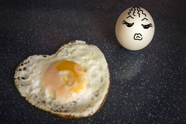 Míchané vajíčko ve formě srdce, ten chlap shořel, zemřel z lásky. Druhé vejce nesdílí jeho pocity, je lhostejné. Horké srdce a chlad. Obrázek je vytvořen autorem. - Fotografie, Obrázek