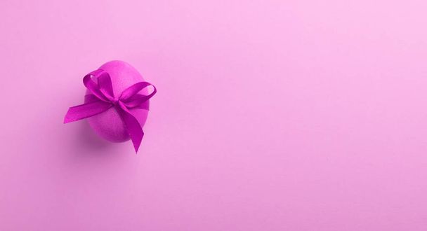 Leuchtend rosa Ei mit einer Satinschleife auf rosa Hintergrund. Festliches Frühlingskonzept. Farbtrend. Selektive Nahaufnahme. - Foto, Bild