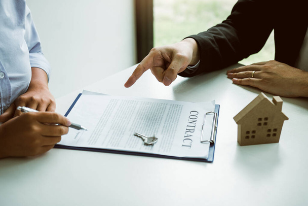 Verzekeringsmakelaars wijzen op de ondertekening van verzekeringscontracten en leggen klanten op kantoor uit. - Foto, afbeelding
