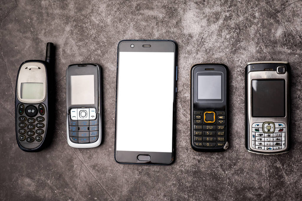 Sok elavult mobiltelefon és egy okostelefon grunge háttérrel. - Fotó, kép