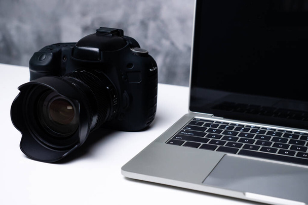 Czarna kamera cyfrowa i laptop na stole. - Zdjęcie, obraz