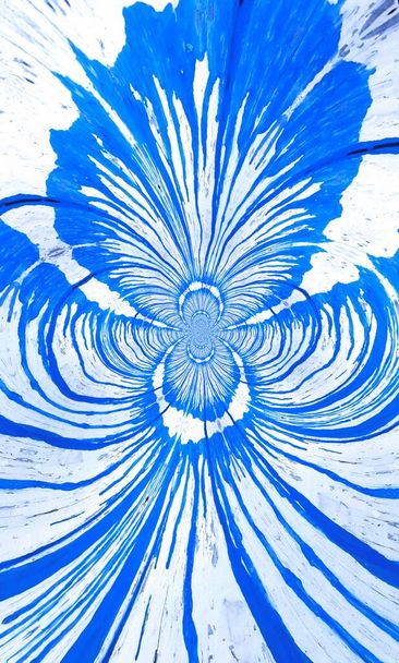 Strahlend blauer und sauberer weißer Farbtropfen fließen senkrecht verlaufende Linien, die sich in eine Reihe von einzigartigen Mustern und Designs im Zyklonstil verwandeln - Foto, Bild