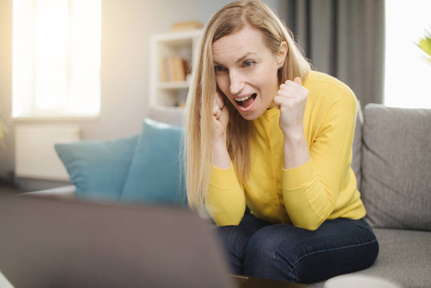 Érzelmes nő néz számítógép képernyő kanapén - Fotó, kép