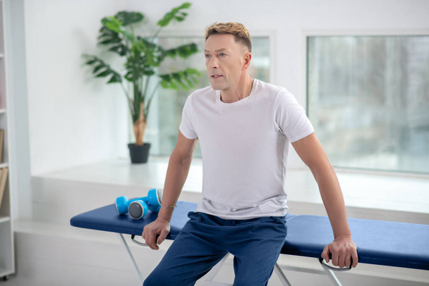 Male physiotherapist sitting on couch, waiting for patient - Foto, Bild