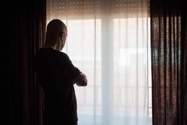 Man locked up at home. Looking through the window. Covid coronavirus quarantine - Foto, Bild