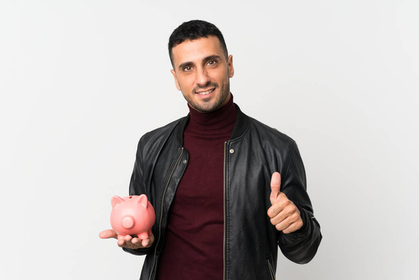 Young man over isolated white background holding a big piggybank - Photo, Image