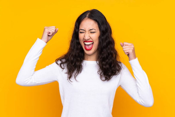 Mixed race woman over isolated yellow background celebrating a victory - Photo, Image