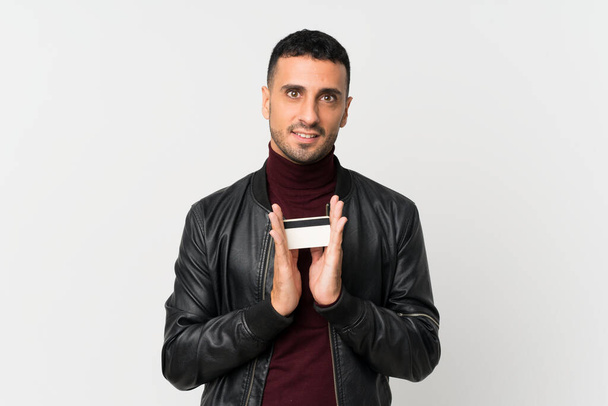 Fiatal férfi izolált fehér háttér kezében hitelkártya - Fotó, kép