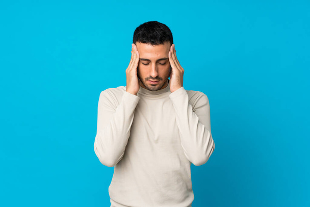 Mladý muž přes izolované modré pozadí s bolestí hlavy - Fotografie, Obrázek