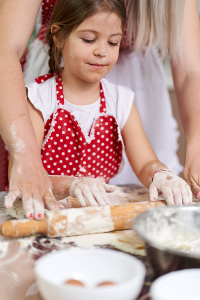 Little girl and her mother kneading dough with roller pin - Φωτογραφία, εικόνα