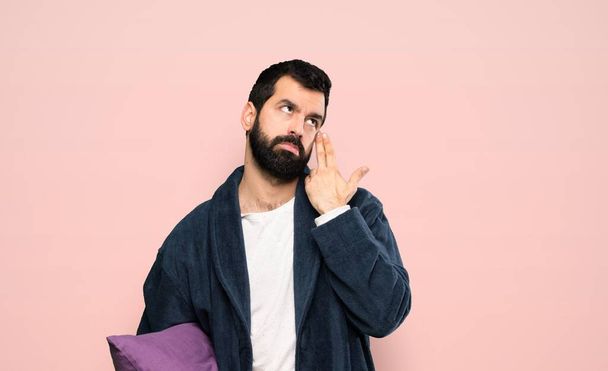 Muž s vousy v pyžamu s problémy dělat sebevražedné gesto přes izolované růžové pozadí - Fotografie, Obrázek