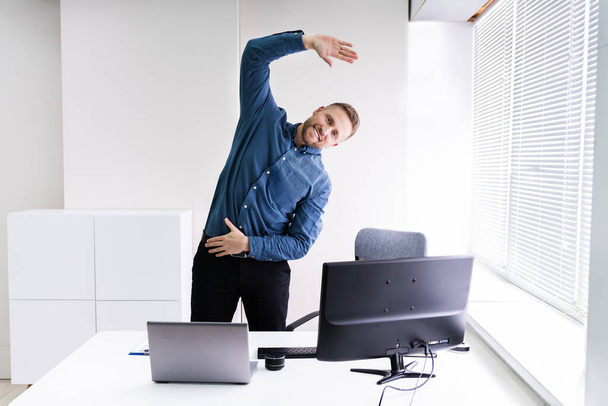 Young Businessman Doing Stretching Exercise In Office - Valokuva, kuva