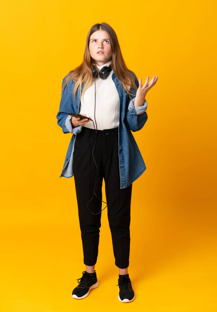 Student ukrainian teenager girl over isolated yellow background unhappy and frustrated with something - Foto, Imagen