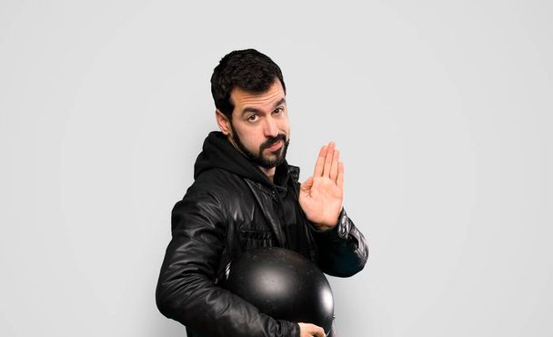 Biker man making stop gesture and disappointed over isolated grey background - Foto, Imagen