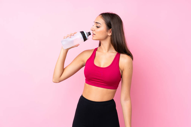 jong sport meisje over geïsoleerde roze achtergrond met sport water fles - Foto, afbeelding