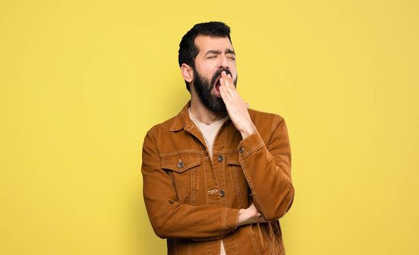 Schöner Mann mit Bart gähnt und deckt weit geöffneten Mund mit der Hand ab - Foto, Bild