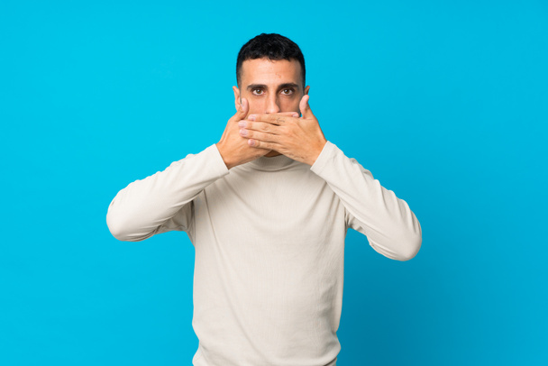 Jeune homme sur fond bleu isolé couvrant la bouche avec les mains
 - Photo, image