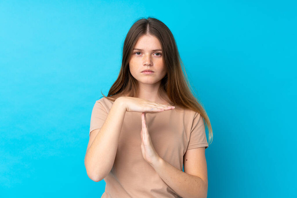Ukrainian teenager girl over isolated blue background making time out gesture - Photo, Image