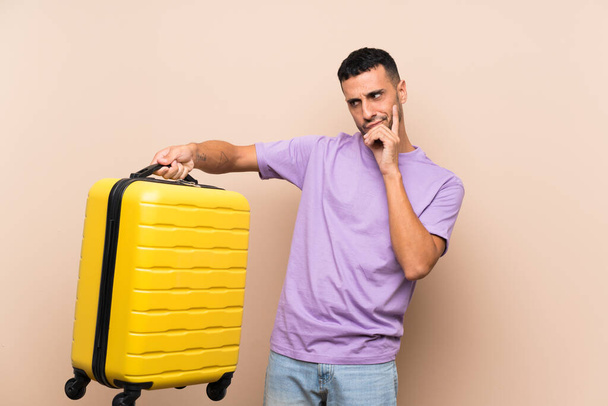 Mężczyzna trzymający walizkę na odosobnionym tle ze smutnym wyrazem twarzy - Zdjęcie, obraz
