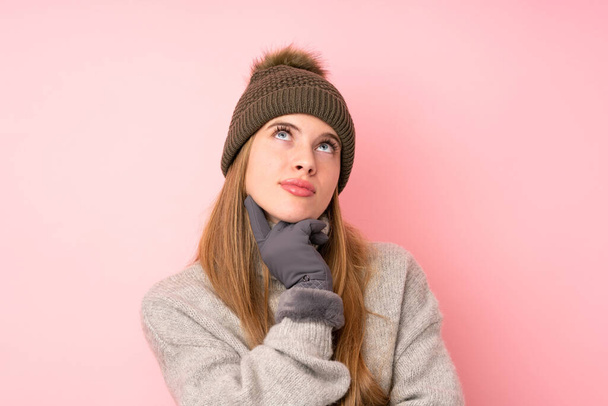 Jovem adolescente com chapéu de inverno sobre fundo rosa isolado pensando uma ideia
 - Foto, Imagem