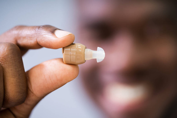 Close-up Of A Happy Man Holding Hearing Aid - Photo, image