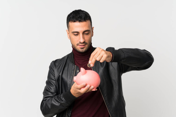 Young man over isolated white background holding a big piggybank - Photo, Image