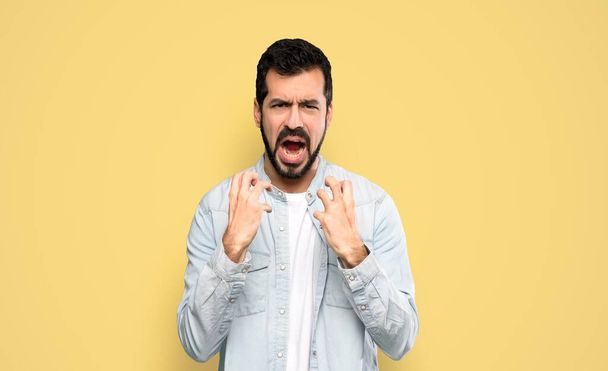 Handsome man with beard frustrated by a bad situation over isolated yellow background - Photo, Image
