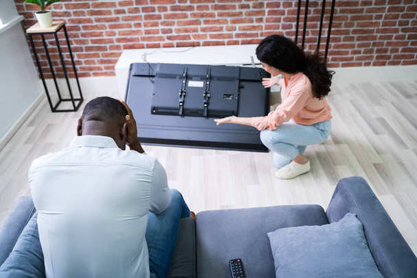 Couple Looking At Fallen Television With Broken Screen - Photo, image