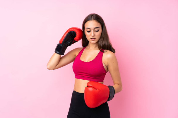 Joven chica deportiva sobre fondo rosa aislado con guantes de boxeo - Foto, Imagen