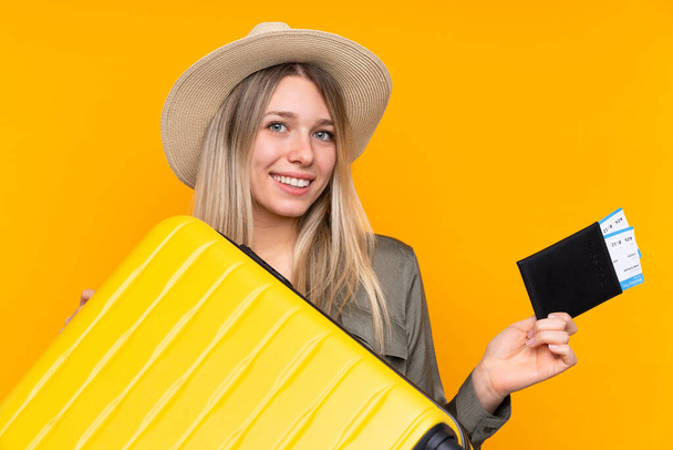 Young blonde woman over isolated yellow background in vacation with suitcase and passport - Foto, immagini