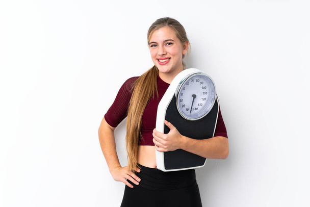 Teenager girl with weighing machine over isolated white background with weighing machine - Фото, зображення