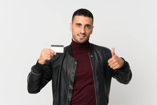 Nuori mies yli eristetty valkoinen tausta jolla luottokortti
 - Valokuva, kuva
