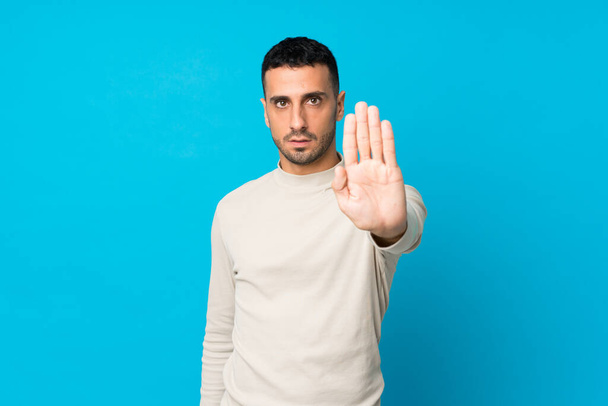 Молодой человек на изолированном синем фоне делает остановку жест
 - Фото, изображение