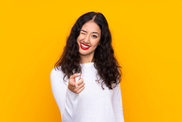 Mixed race woman over isolated yellow background points finger at you - Photo, Image