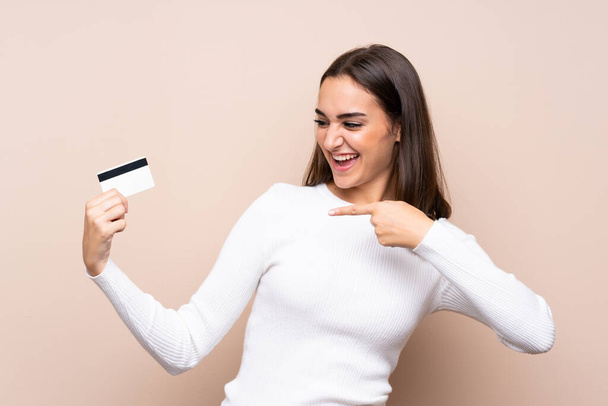 Νεαρή γυναίκα σε απομονωμένο φόντο με πιστωτική κάρτα - Φωτογραφία, εικόνα