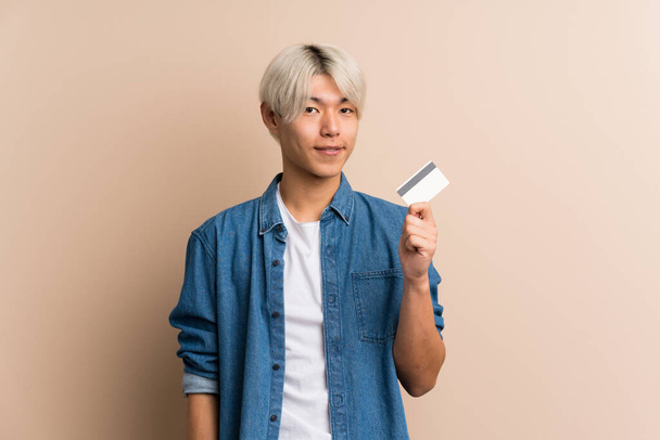 Young asian man over isolated background holding a credit card - Fotografie, Obrázek