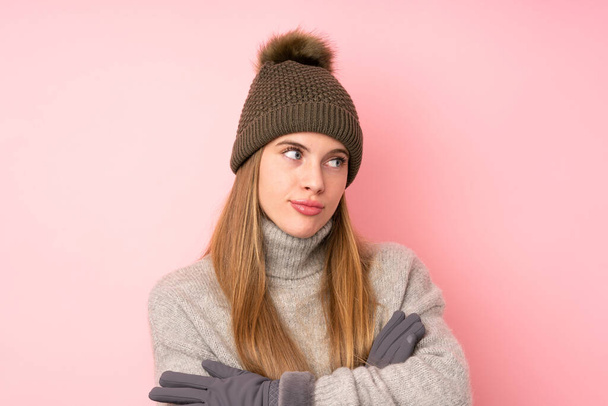 junges Teenager-Mädchen mit Wintermütze über isoliertem rosa Hintergrund denkt eine Idee - Foto, Bild