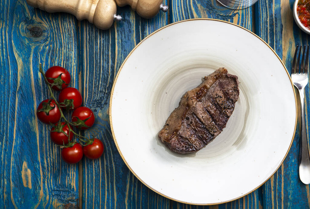 Grilled steak ,cherry tomatoes salt and pepper on wooden table. - Фото, зображення