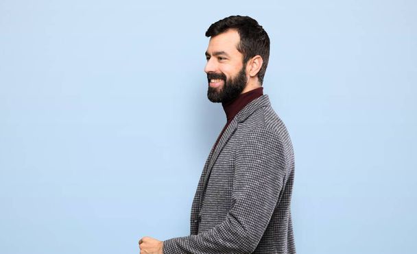 Happy Handsome man with beard walking over isolated blue background - Foto, immagini