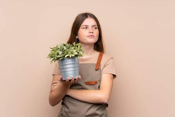 Ukraynalı genç bahçıvan kız elinde bir bitki tutarak bir fikir düşünüyor. - Fotoğraf, Görsel