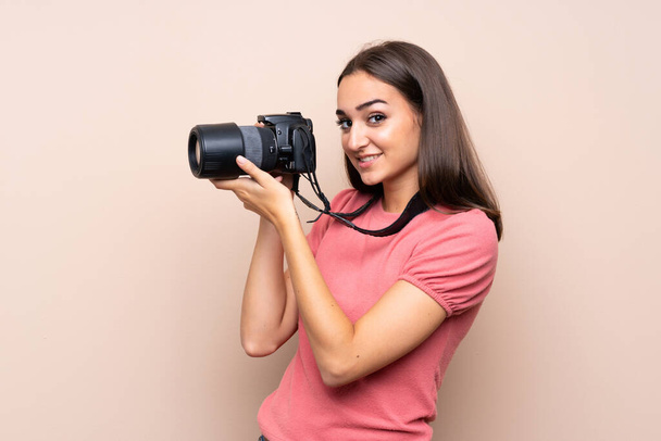 jonge vrouw over geïsoleerde achtergrond met een professionele camera - Foto, afbeelding