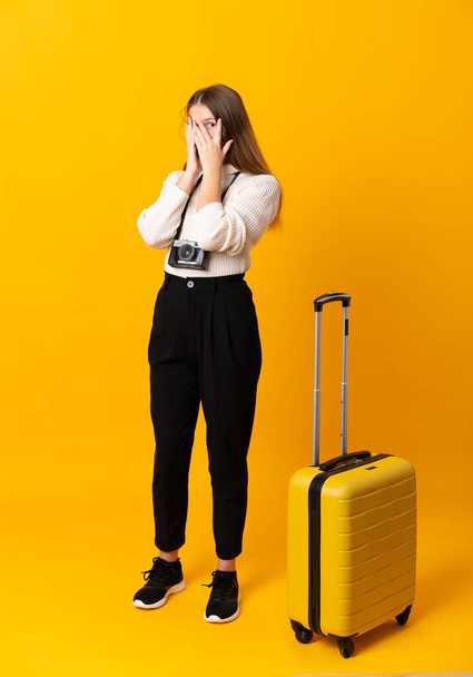フルボディの旅行ティーン女の子とともにスーツケース上の隔離された黄色の背景カバー目と見透かし指 - 写真・画像