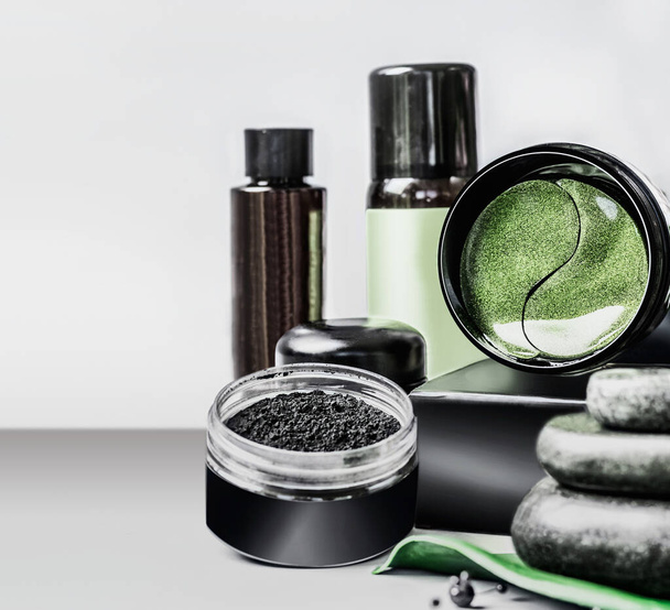 Cosmetics setting ads. Black package template with charcoal powder and green eye patches . Branding mock up. Charcoal cosmetic set. Facial skin care . Beauty blog promotion. Cosmetic store . - Фото, изображение