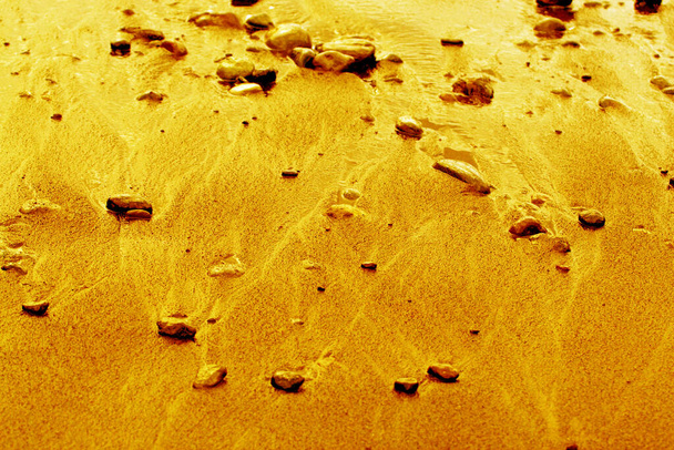 zandstrand met kiezelstenen bij eb, in oranje - Foto, afbeelding