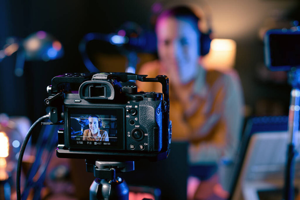Junge Youtuberin nimmt Video in ihrem Studio auf, professionelle Kamera im Vordergrund - Foto, Bild