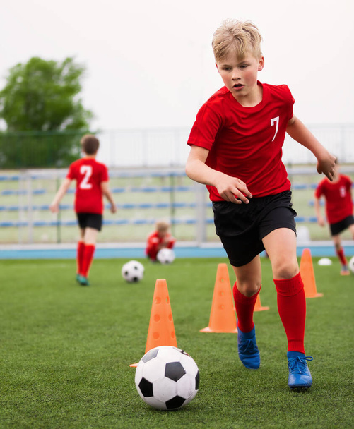 Soccer Boy on Training with Ball and Soccer Cones. Dribbling Drill. Soccer Kids Dribble Training. Youth Soccer Club Practice Session. Boys in Sports Team in Red Soccer Uniforms - Foto, Imagem