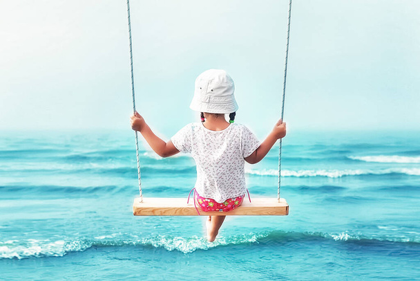 menina em um balanço sobre o mar
 - Foto, Imagem