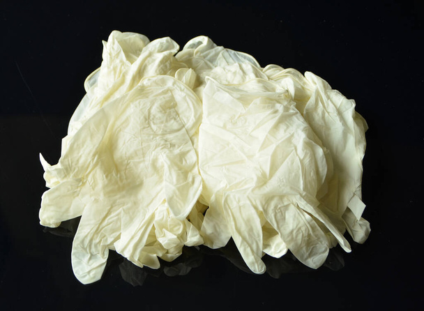 Концепція коронавірусу. Одноразові білі медичні латексні рукавички на чорному тлі. Правила гігієни під час епідемії коронавірусу. Концепція медичного обладнання
. - Фото, зображення