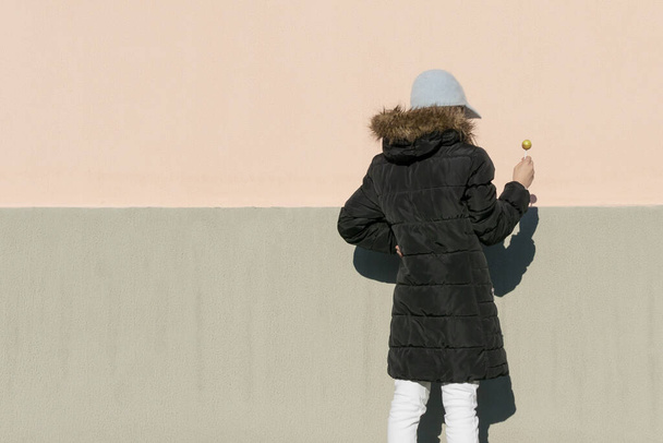 A young girl in a dark jacket with a round candy poses in front of the camera - Foto, Imagem