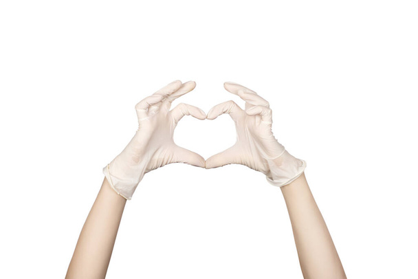 Un gesto de mano. Mano en un guante de látex blanco que muestra el signo del corazón aislado sobre fondo blanco. Amor, paz y seguridad
 - Foto, Imagen